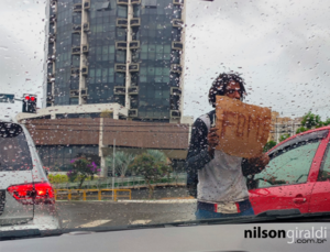 foto de pessoa em situação de rua com cartaz escrito fome.