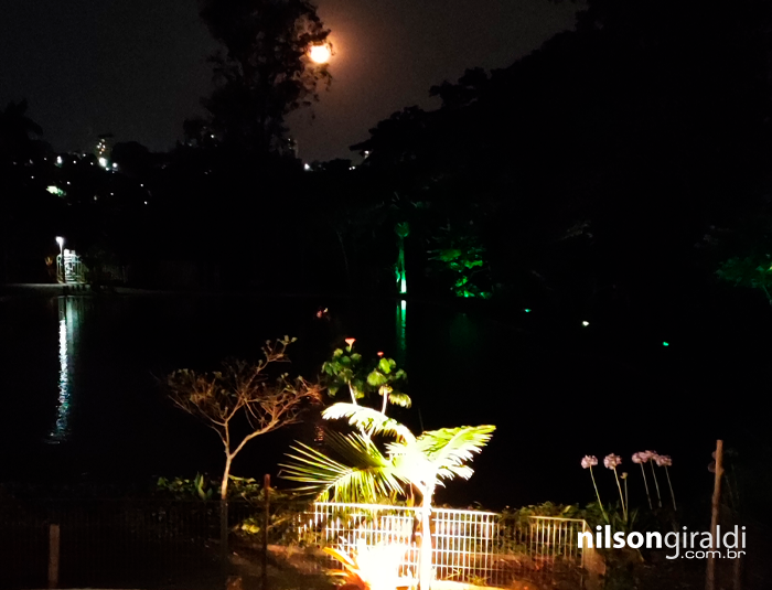 Foto noturna com lua cheia sobre o lago.